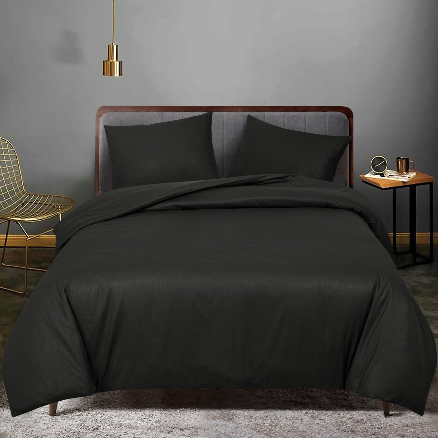 Black bedding set on a bed in a bedroom with a gray wall and gold chair, featuring ZM Textiles Belgium dyed duvet cover set.