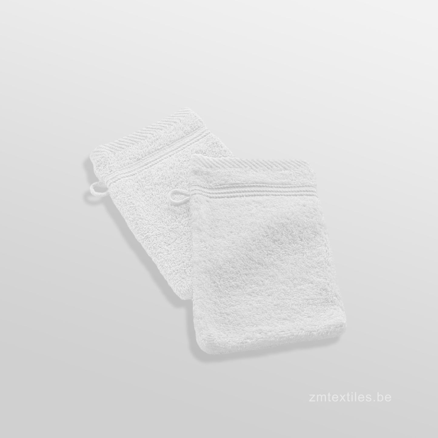 White textured bath mat on a light gray background, featuring ZM Textiles Belgium soft wash gloves.