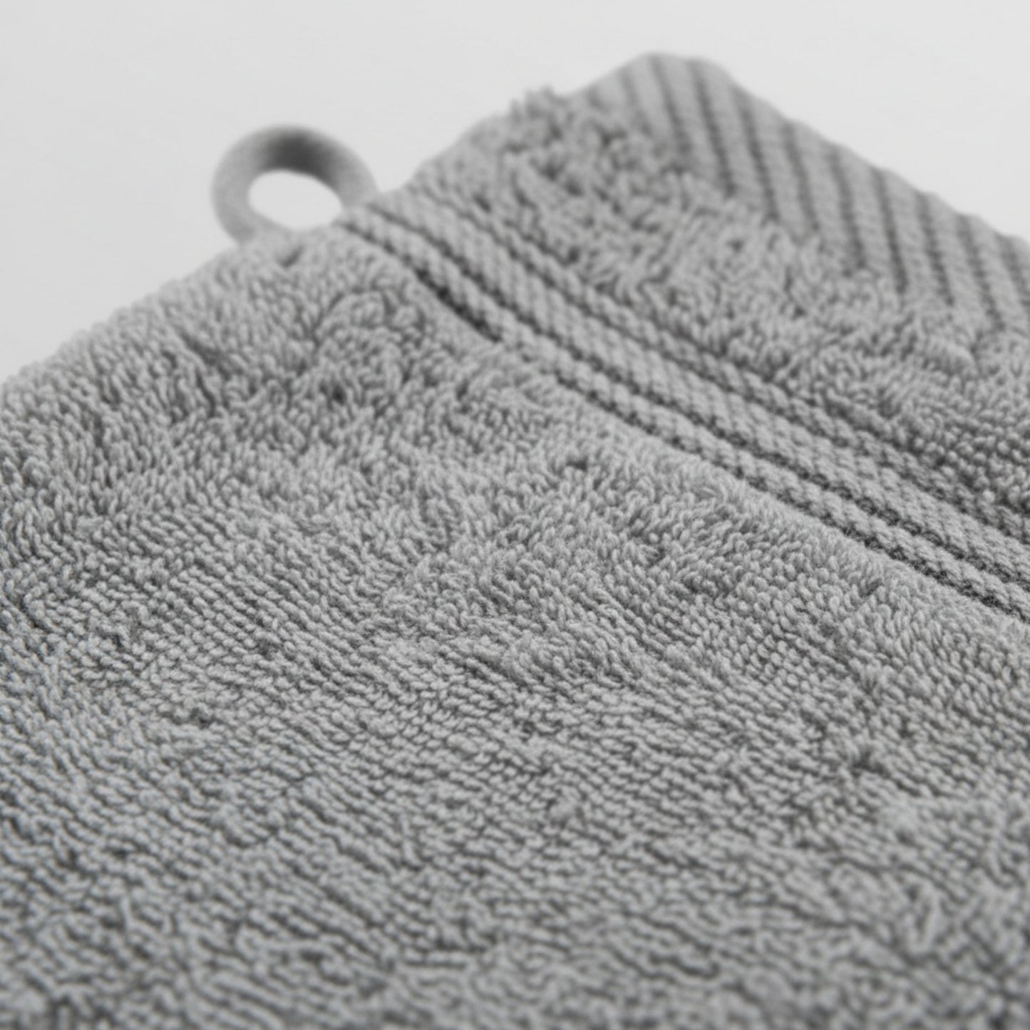 Gray textured wash glove with a circular hole, likely for hanging, featuring ZM Textiles Belgium wash gloves.