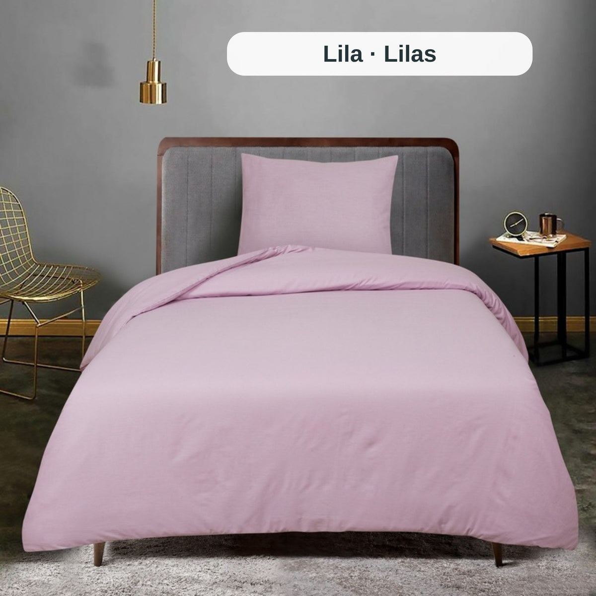 Rosa Bettwäsche-Set auf einem Bett in einem Raum mit grauer Wand und goldenem Stuhl, mit dem uni Bettbezug-Set von ZM Textiles Belgium.