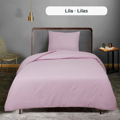 Rosa Bettwäsche-Set auf einem Bett in einem Raum mit grauer Wand und goldenem Stuhl, mit dem uni Bettbezug-Set von ZM Textiles Belgium.