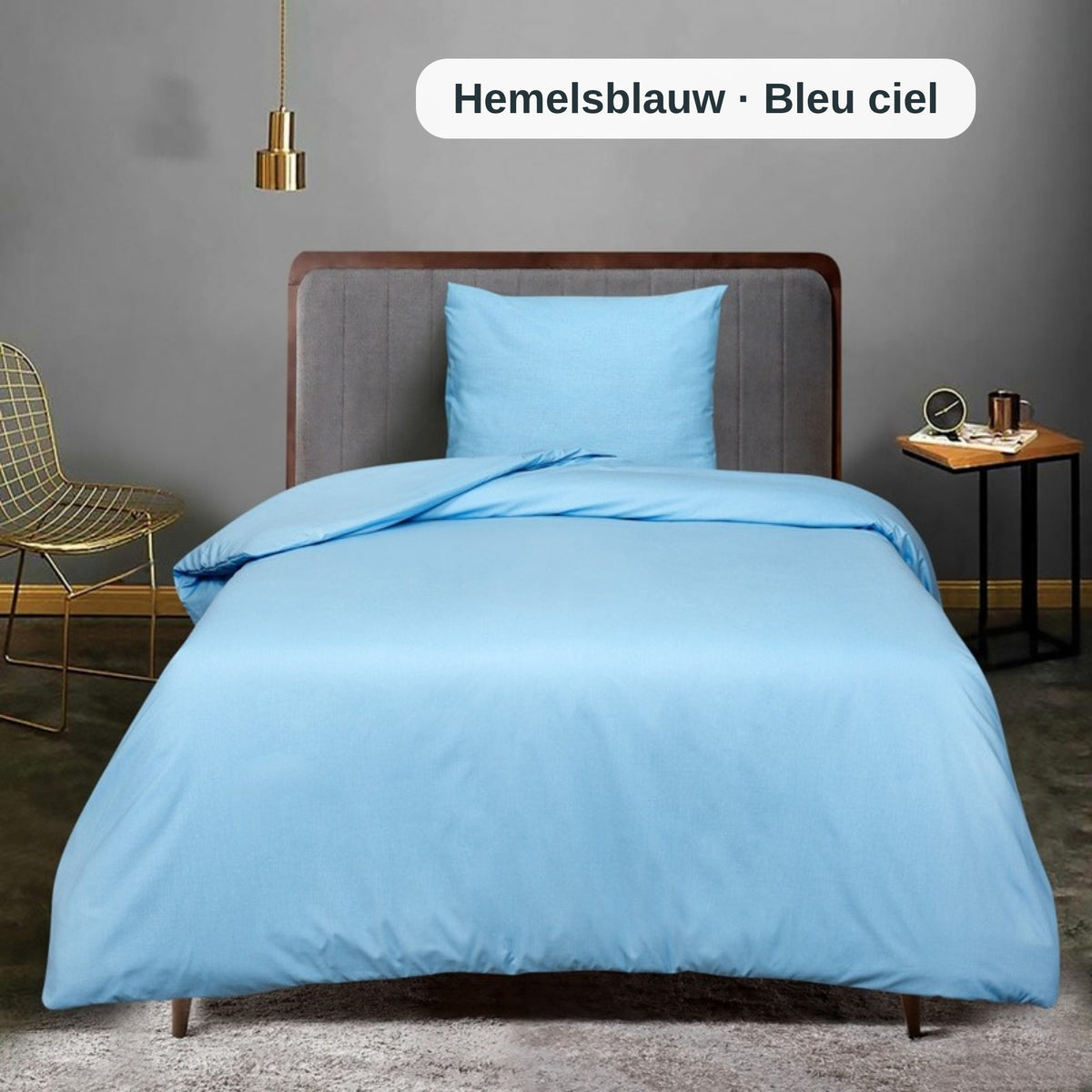 Blaues Bettwäsche-Set auf einem Bett in einem modernen Schlafzimmer mit grauer Wand und hölzernem Nachttisch, mit dem uni Bettbezug-Set von ZM Textiles Belgium.