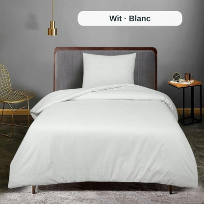 Schlafzimmer mit ordentlich gemachtem Bett mit weißer Bettwäsche und Kopfteil aus Holz, mit dem uni Bettbezug-Set von ZM Textiles Belgium.