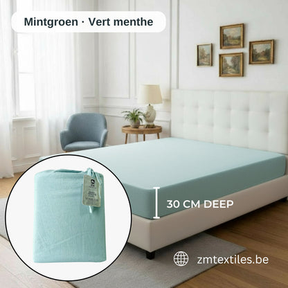 Blauer Matratzenbezug mit Etikett auf einem Bett in einem Schlafzimmer, mit den Flanell-Spannbettlaken von ZM Textiles Belgium.