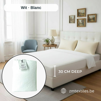 Bett mit weißem Matratzentopper und Kissen in einem Schlafzimmer, mit den Flanell-Spannbettlaken von ZM Textiles Belgium.